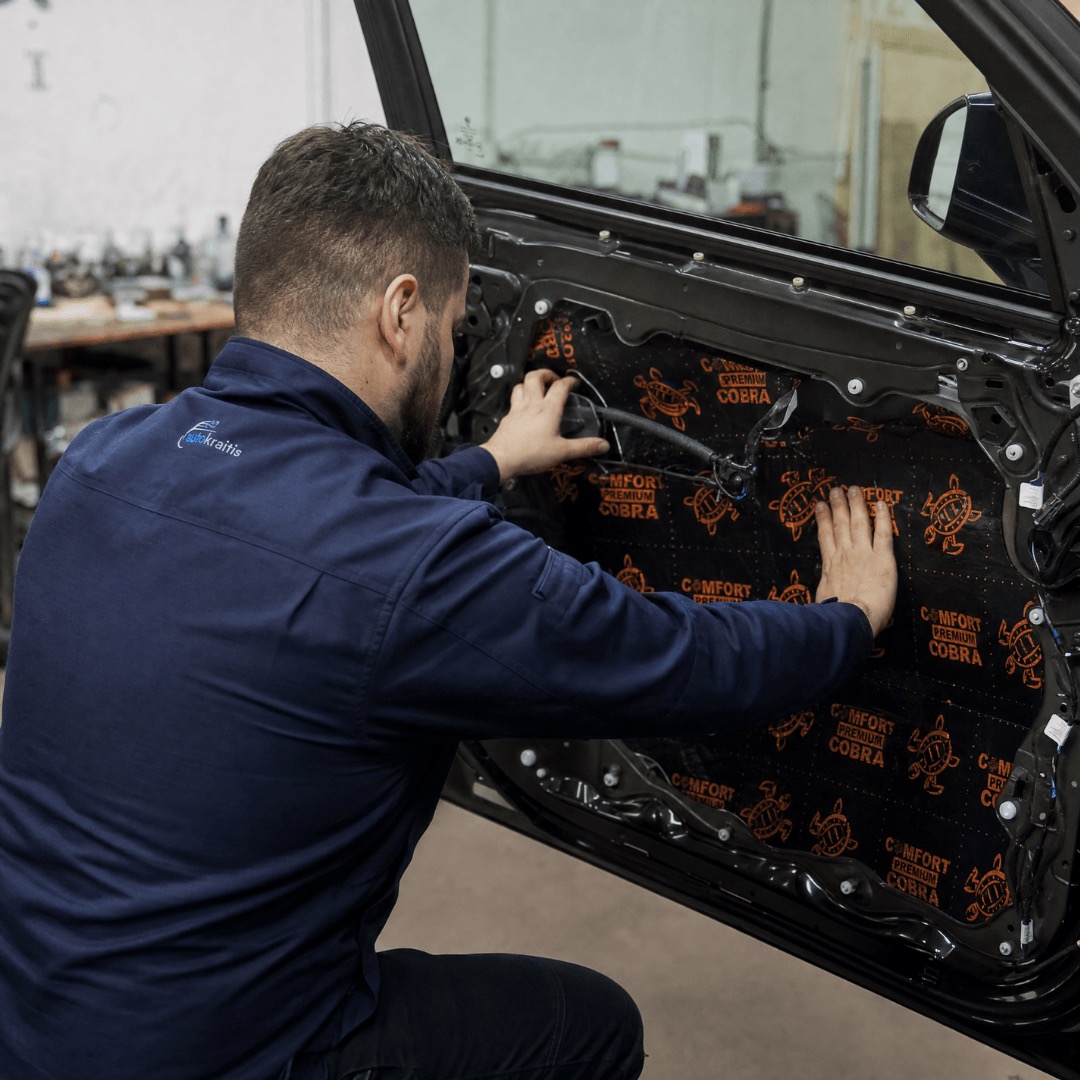 Meistras klijuoja garso izoliacijos medžiagą automobilio durų viduje